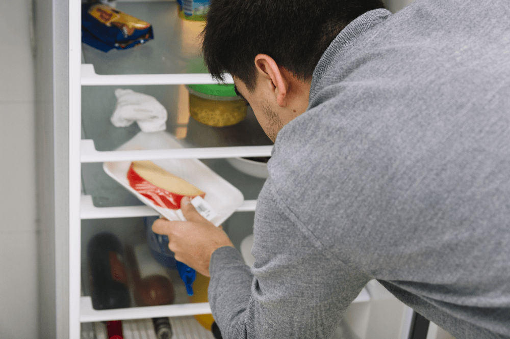 Man putting cheese in the refrigarator