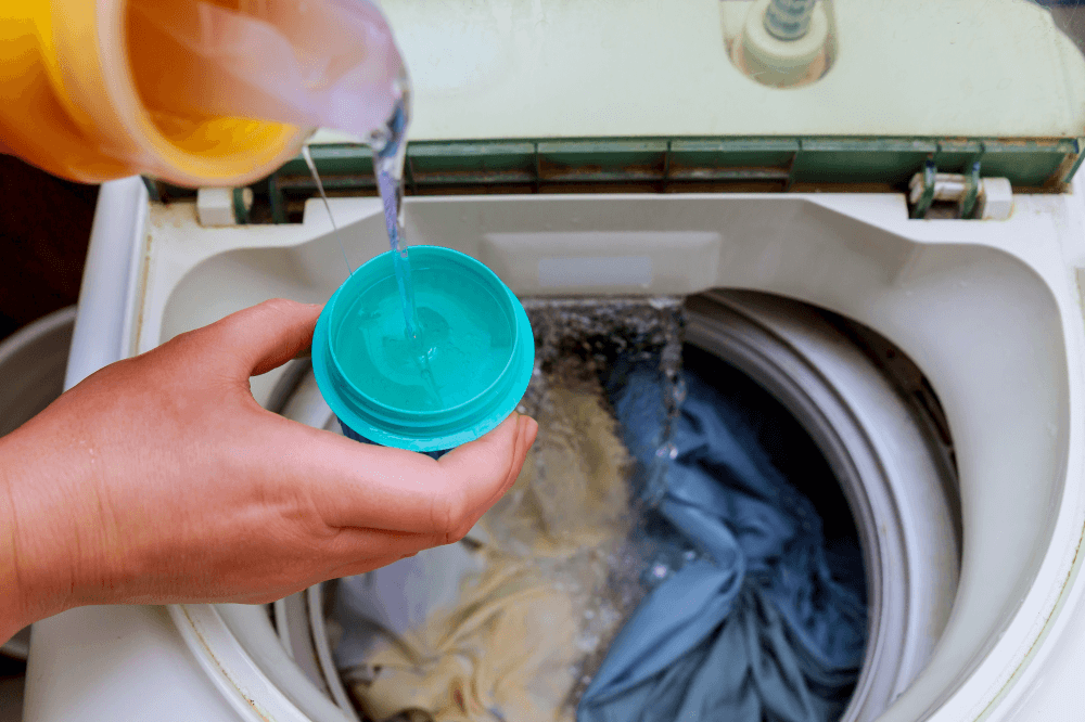 Woman pouring liquid detergent in washing machine