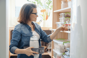 Middle aged woman selecting ingredients from kitchen cabinet